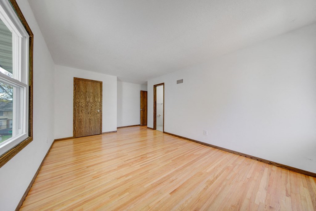 the living room and bedroom of an empty house with wood flooring