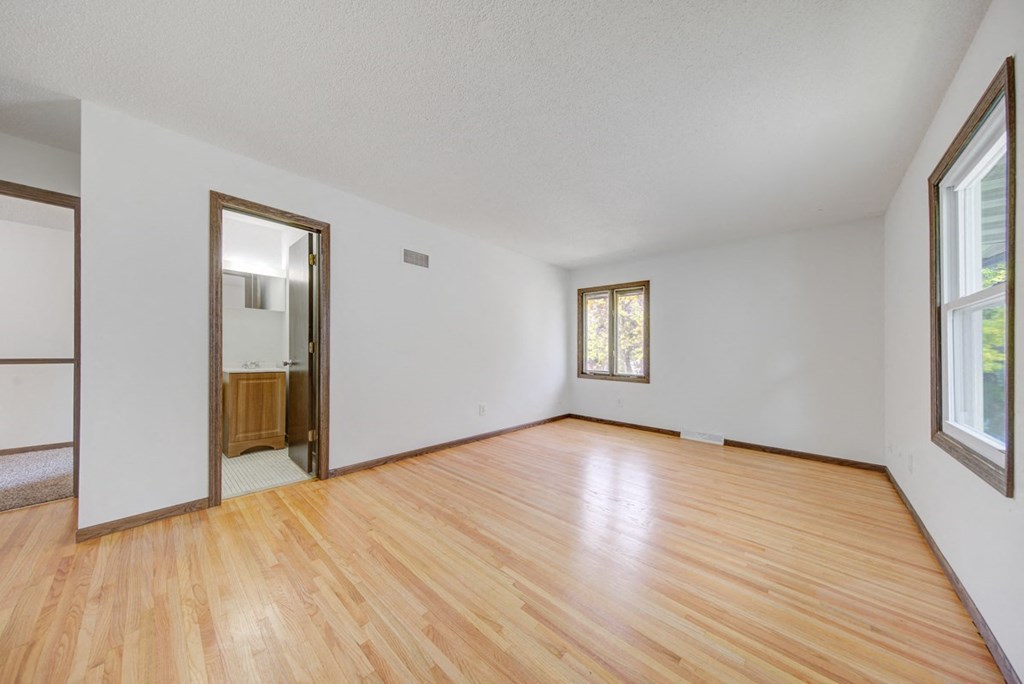 an empty living room with wood floors and white walls