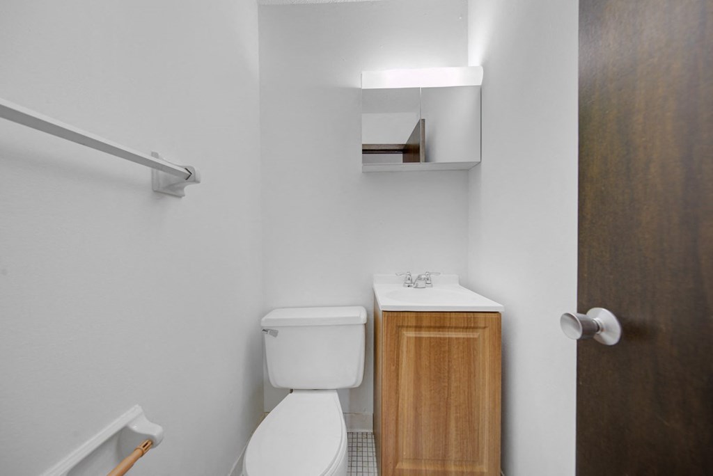 a bathroom with a toilet and a wooden cabinet
