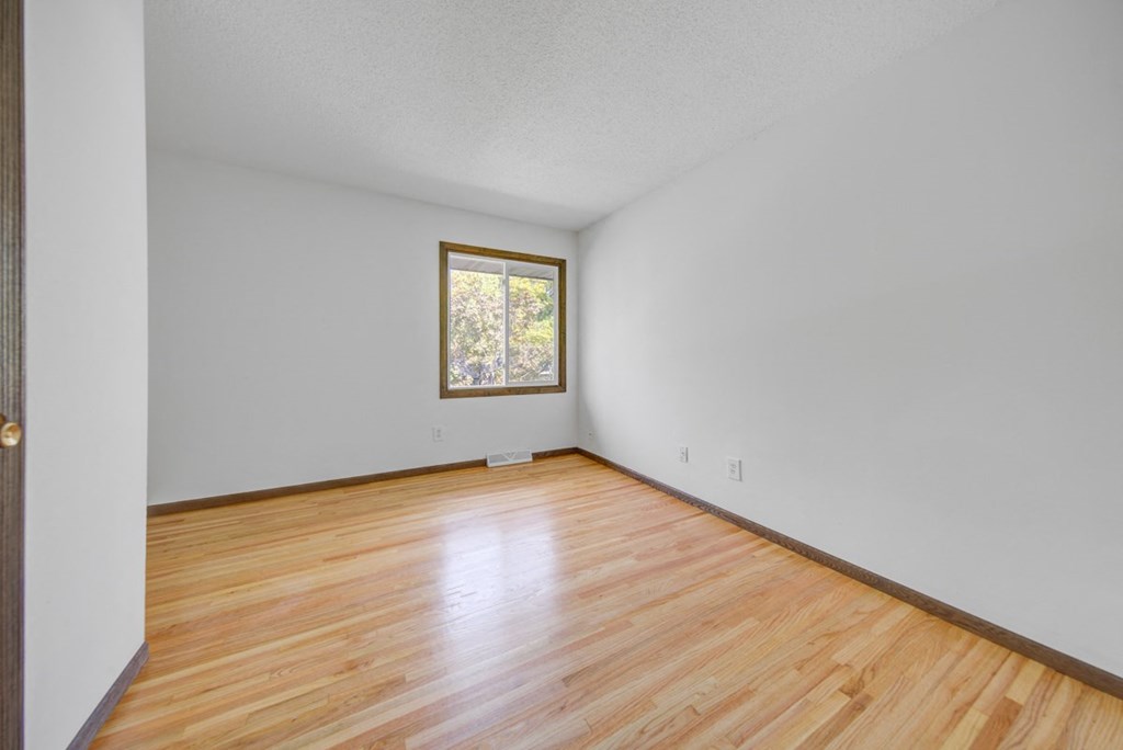 an empty room with wood floors and a window