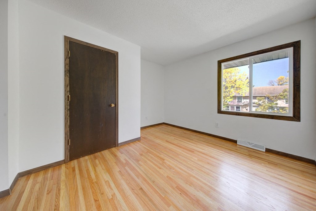 an empty living room with wood floors and a window