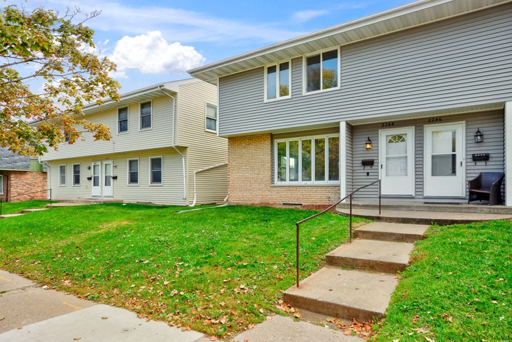 the front of a house with stairs and a lawn