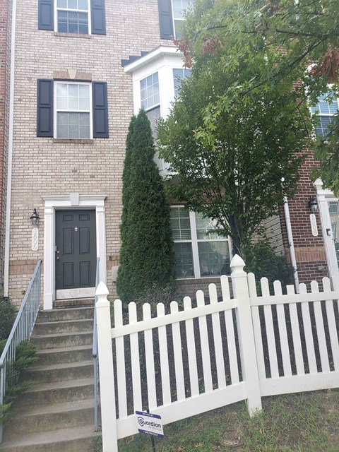 A white picket fence in front of a brick house.