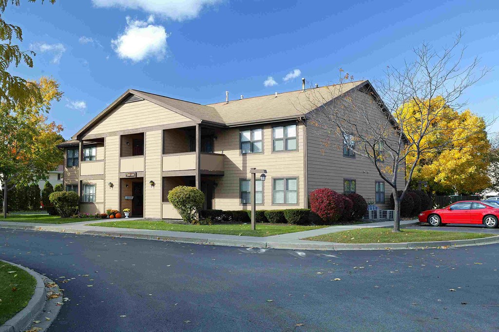 an apartment building with a red car parked outside of it