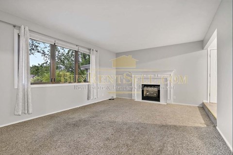 A spacious living room with a fireplace and large windows.