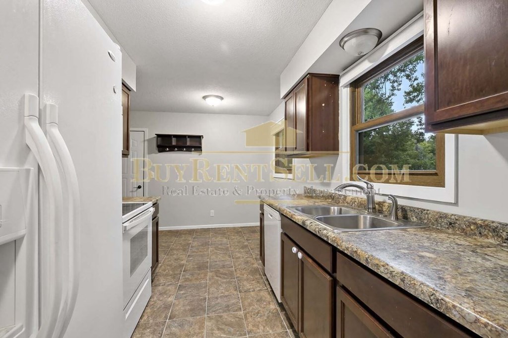 A kitchen with a white refrigerator and brown cabinets.