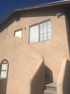 A tan stucco house with a window and a door.