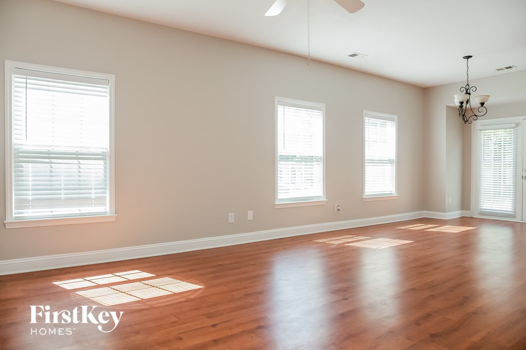 an empty living room with wood floors and three windows