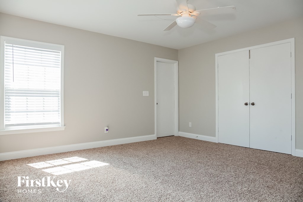a bedroom with a carpeted floor and a ceiling fan