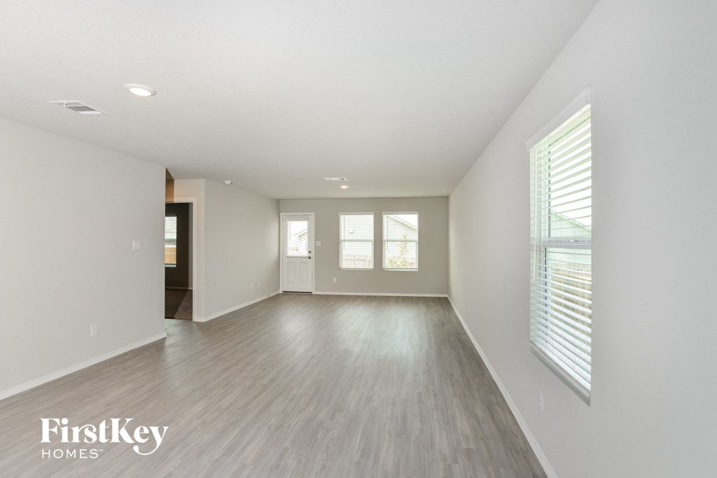 A spacious room with wooden flooring and white walls.