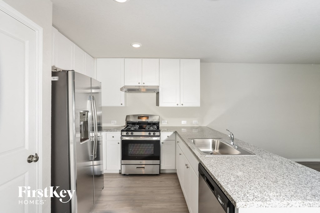 A kitchen with a stove top oven and a refrigerator.