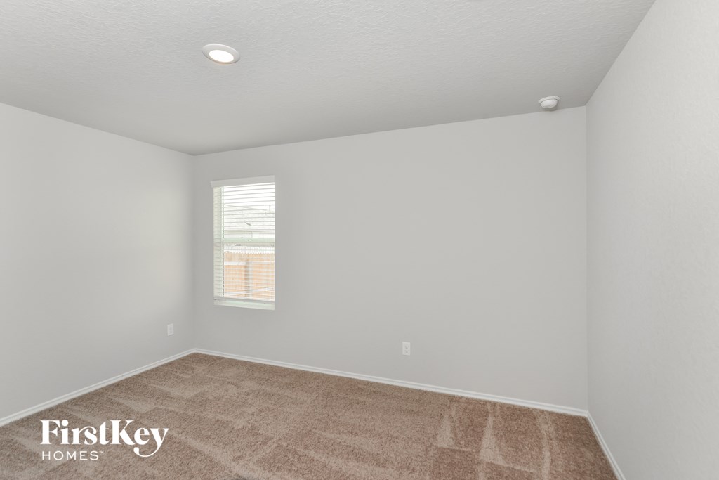 A room with a carpeted floor and a window with blinds.