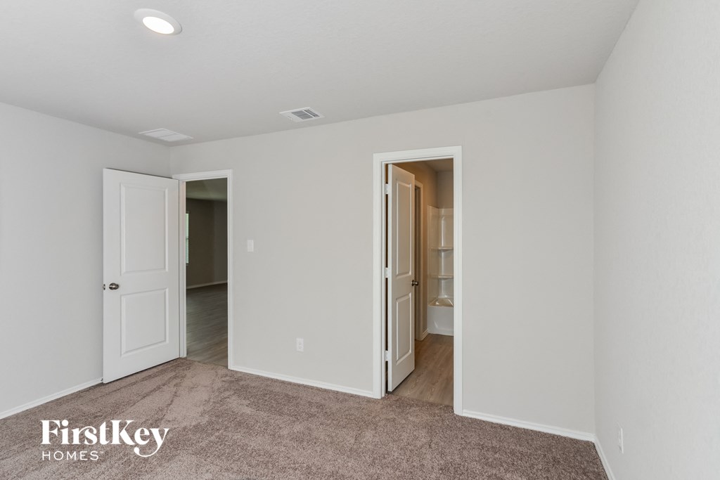 A room with a carpeted floor and two doors, one of which is open.