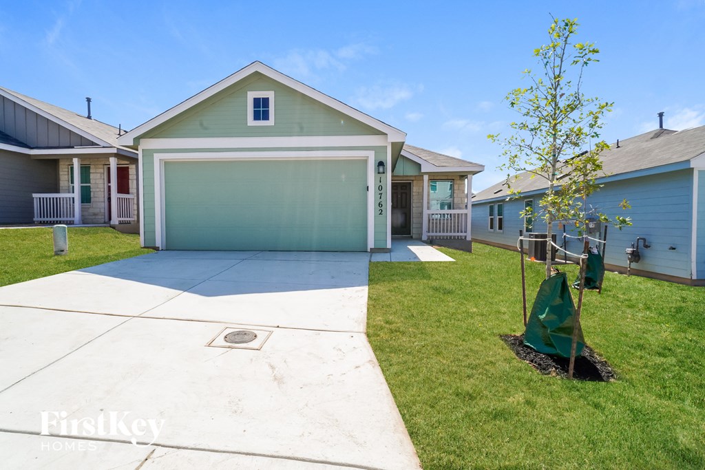 a blue house with a white sidewalk and a small tree