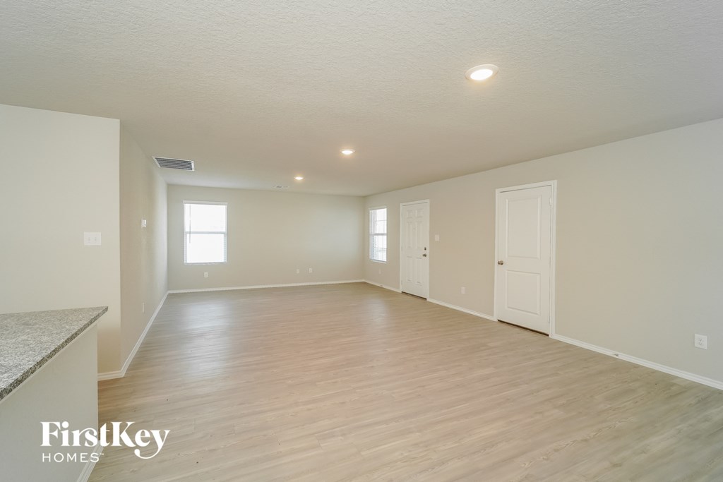 a spacious living room with white walls and wood flooring