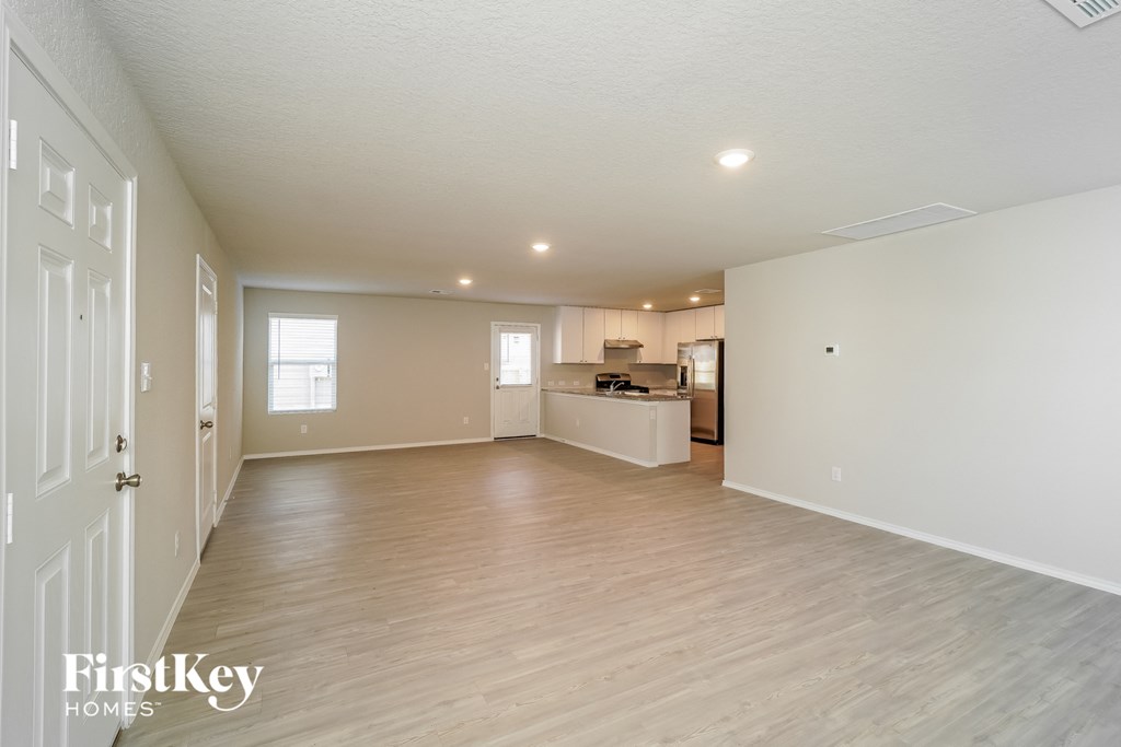 a spacious living room and kitchen with wood flooring and white walls