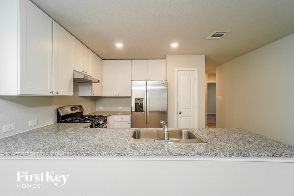 a kitchen with white cabinets and granite counter tops and a sink