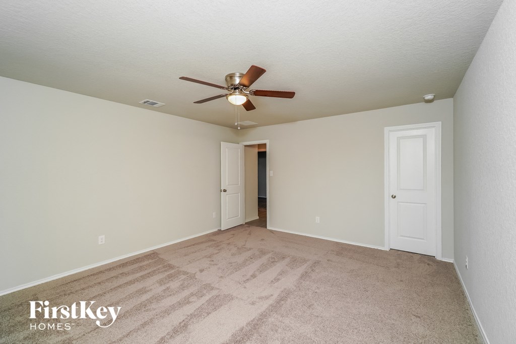 a spacious living room with carpet and a ceiling fan