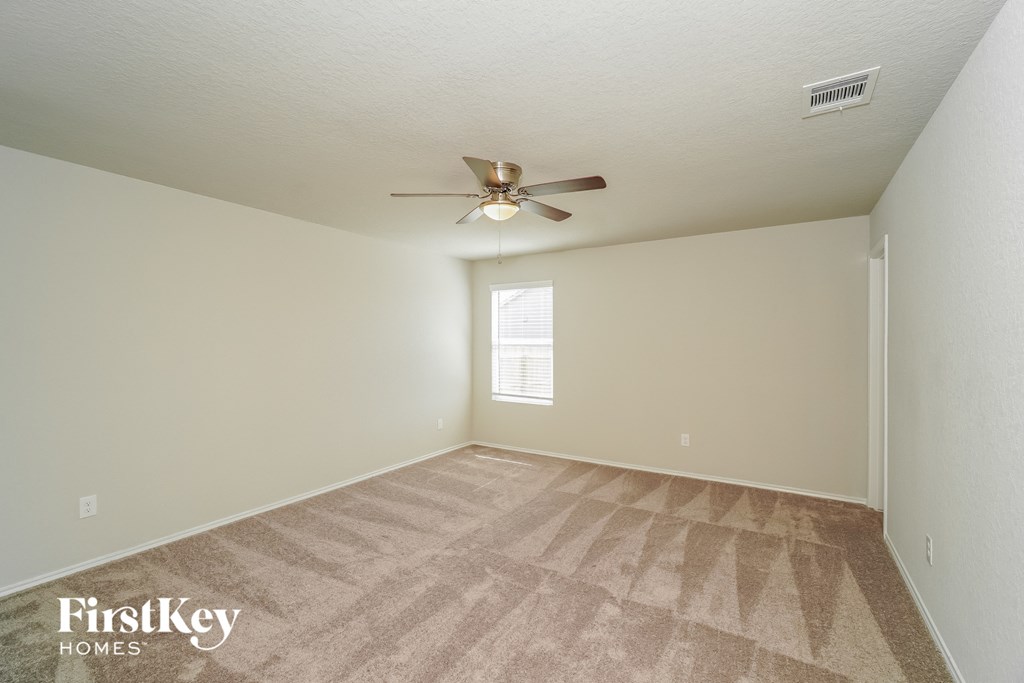 a spacious living room with carpet and a ceiling fan