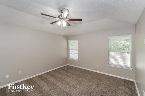 the spacious living room with carpet and ceiling fan