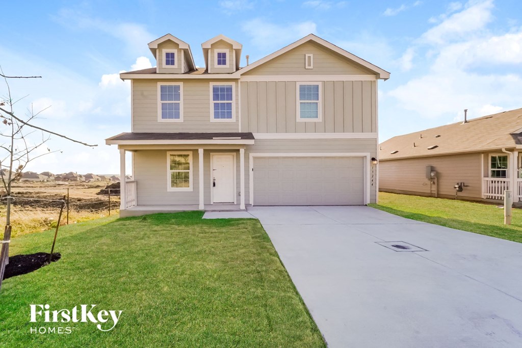 a beige house with a driveway and a lawn