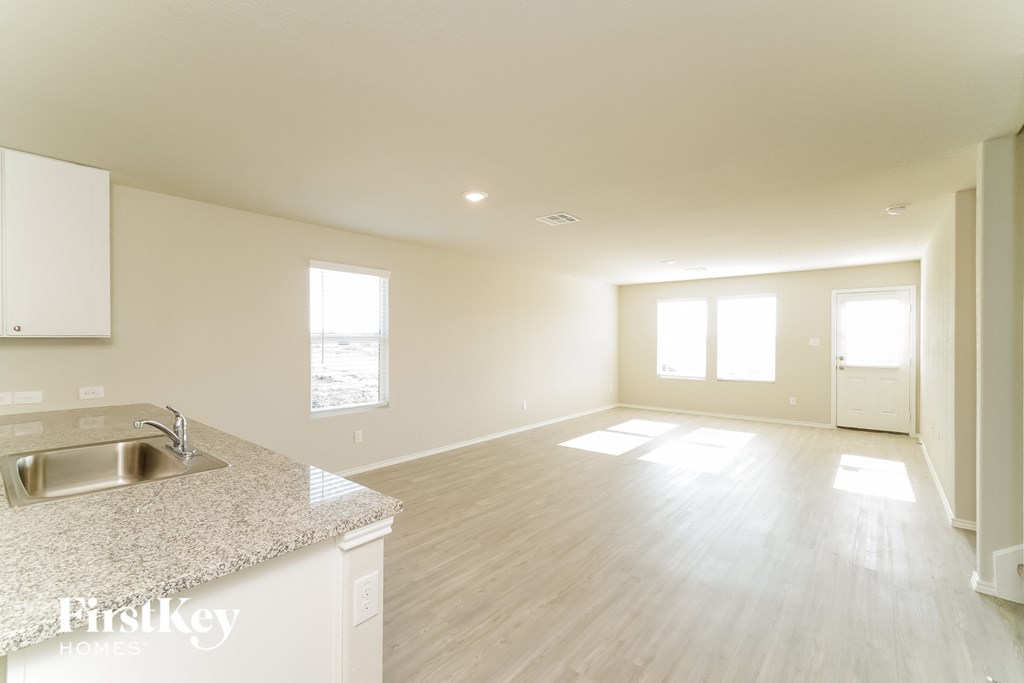 an empty living room and kitchen with a sink