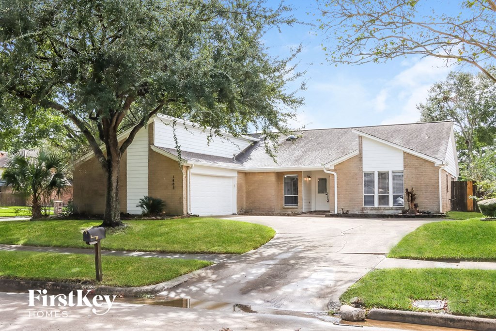 a house with a driveway and a tree in front of it