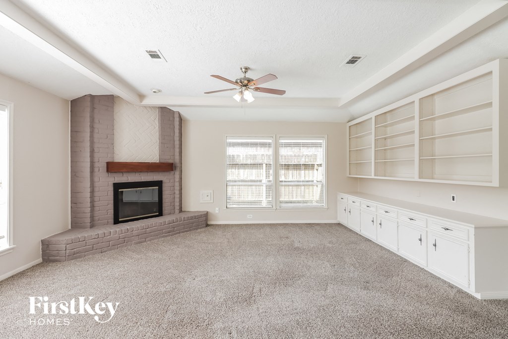 a living room with a fireplace and a ceiling fan