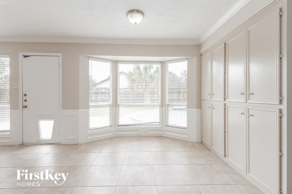 an empty laundry room with white cabinets and a large window