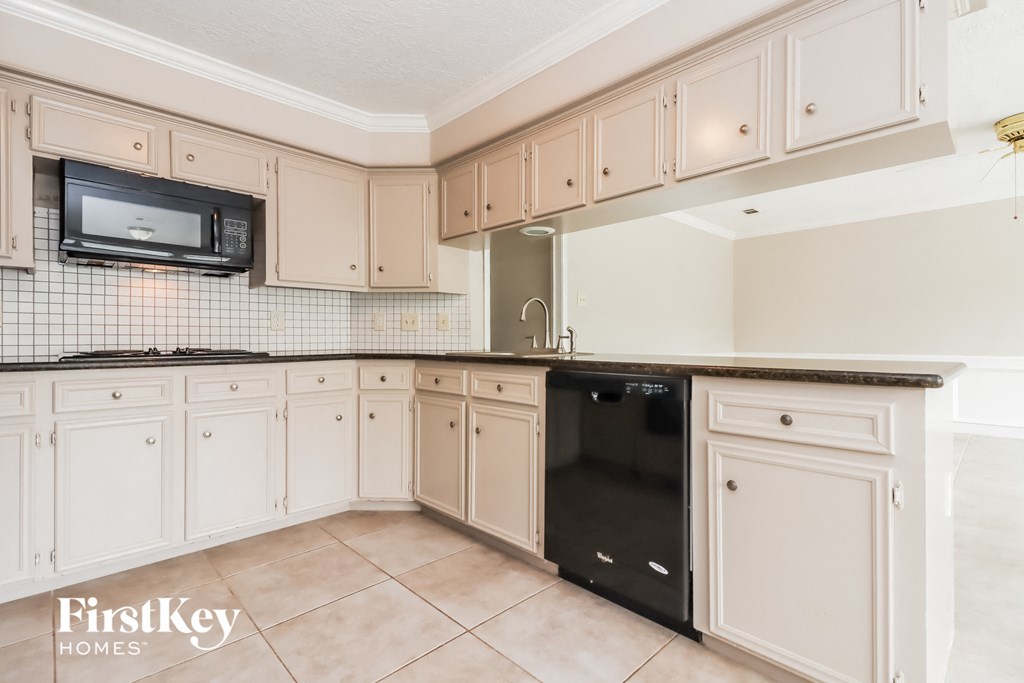 a kitchen with white cabinets and a black dishwasher