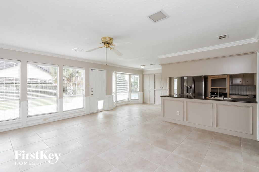 a kitchen and living room with large windows and a ceiling fan