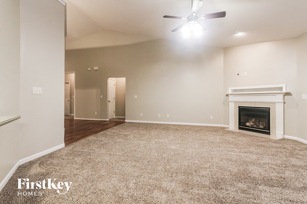 an empty living room with a fireplace and a ceiling fan