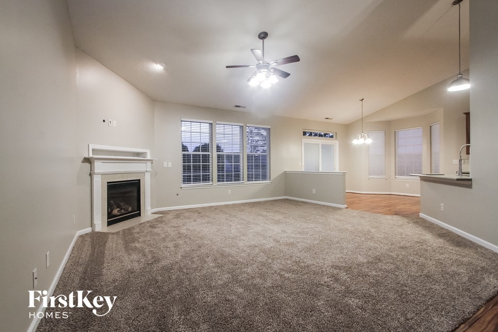 an empty living room with a fireplace and a ceiling fan