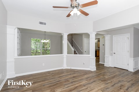 a living room with white walls and a ceiling fan