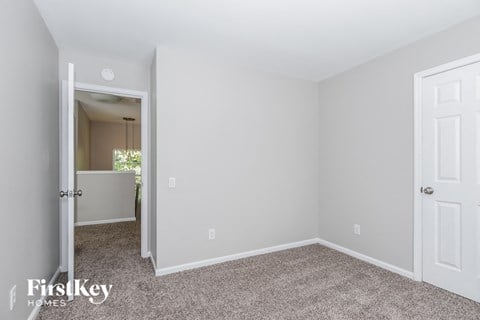 a bedroom with white walls and carpet and a door to a closet