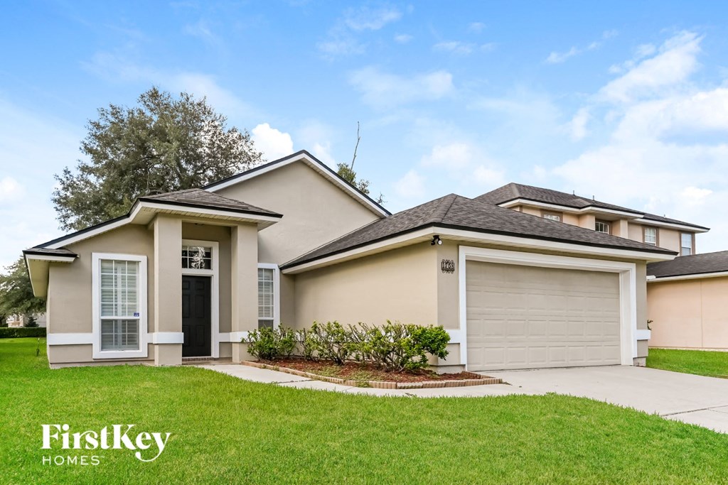 a beige house with a lawn and a driveway