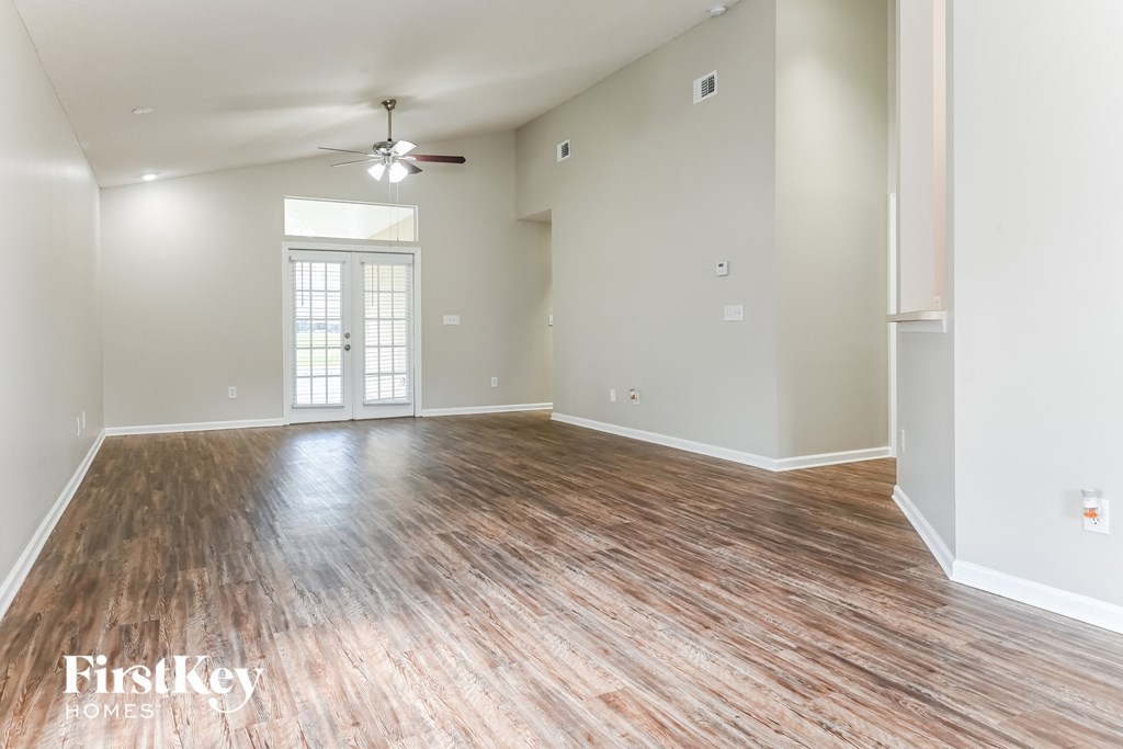 the living room and dining room with wood flooring and a ceiling fan