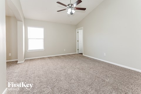 a spacious living room with carpet and a ceiling fan
