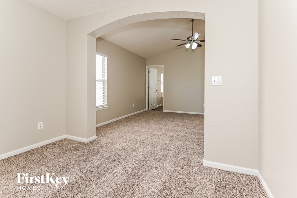 a spacious living room with carpet and a ceiling fan