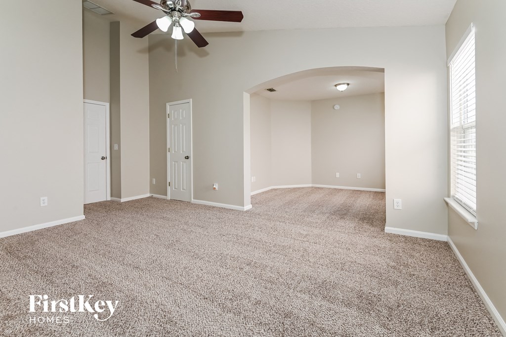 a spacious living room with carpet and a ceiling fan