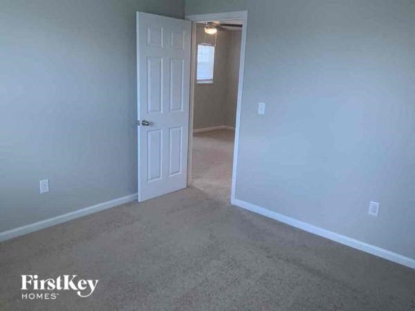 an empty room with a white door and a hallway