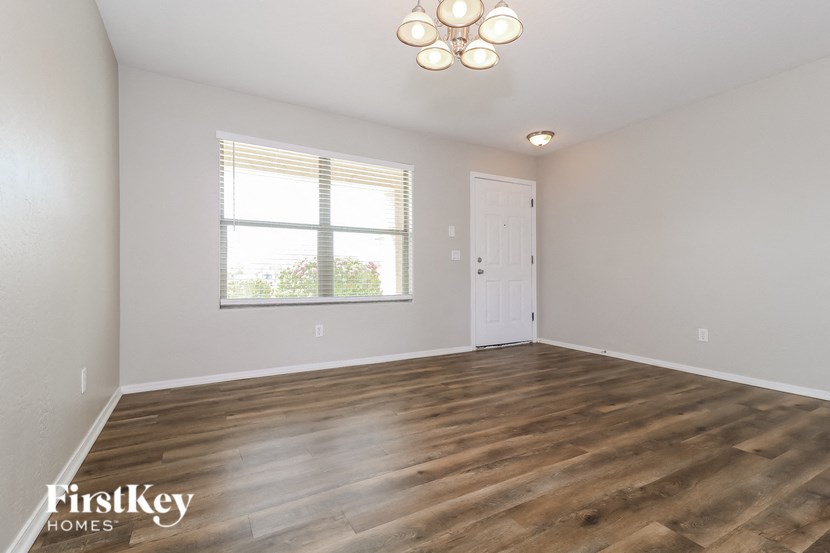 the spacious living room with wood flooring and a window