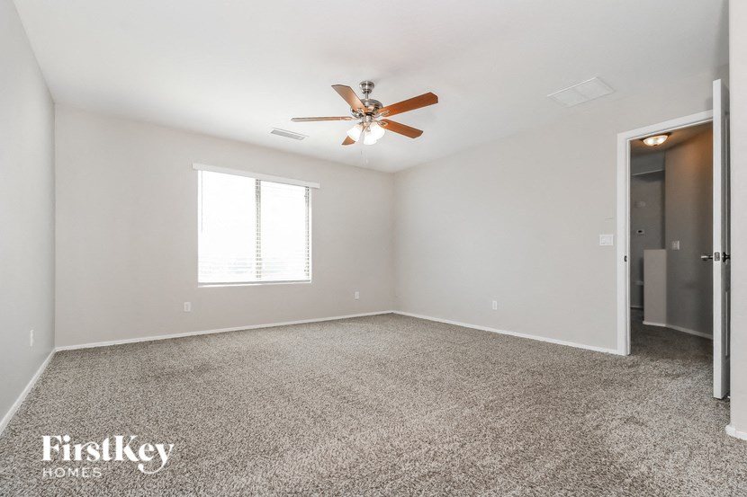 the spacious living room with ceiling fan and carpeting
