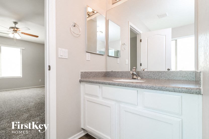 a bathroom with white cabinets and a sink and a mirror
