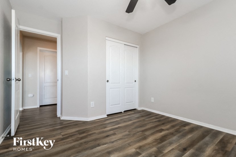 a bedroom with white walls and wood flooring and a closet
