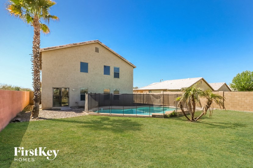 a backyard with a pool and a house with a palm tree