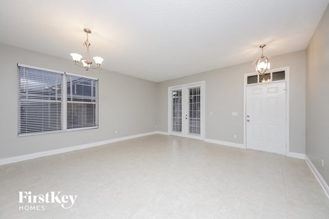A spacious empty room with a chandelier and two doors.
