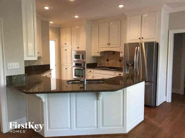 a kitchen with white cabinets and a black counter top