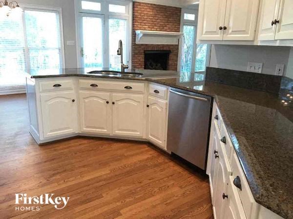 a kitchen with white cabinets and a wood floor