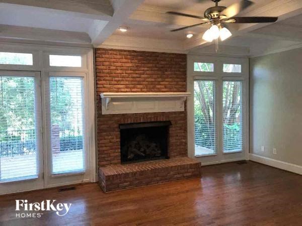 a living room with a brick fireplace and a ceiling fan